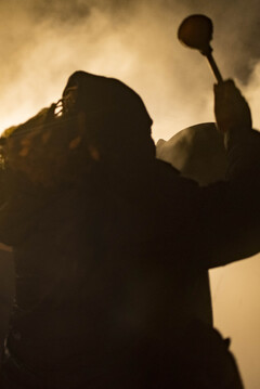 One of the Tribal elders sings and beats his drum down by the fires to inspire hope and keep spirits high in the freezing cold temperatures and fire hoses.