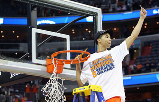 Michael Carter-Williams #1 of the Syracuse Orange holds up the a piece of the net as he cuts it down with teammates.