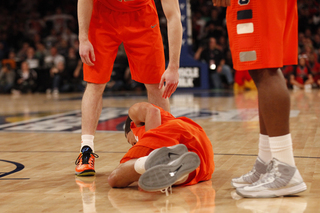 Michael Carter-Williams falls to the ground after taking a hit to the gut.