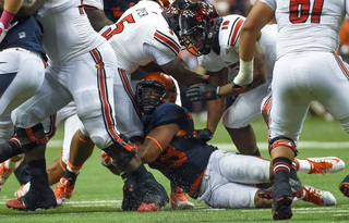 An SU defender tries to bring down Louisville running back Michael Dyer.