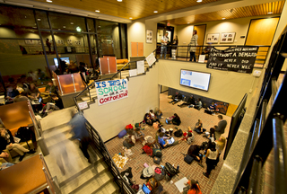 Diversity and Transparency Rally protesters socialize and use their laptops as they plan to spend the night in the Crouse-Hinds Hall lobby on Monday. Protesters plan to stay in the lobby of Crouse-Hinds Hall until Thursday when the Board of Trustees will meet.