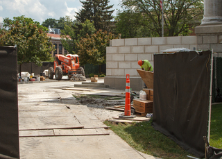 A worker mixes liquids in a bucket near Hendricks Chapel as construction crews replace the front steps to the historic building. Photo taken Aug. 1, 2017